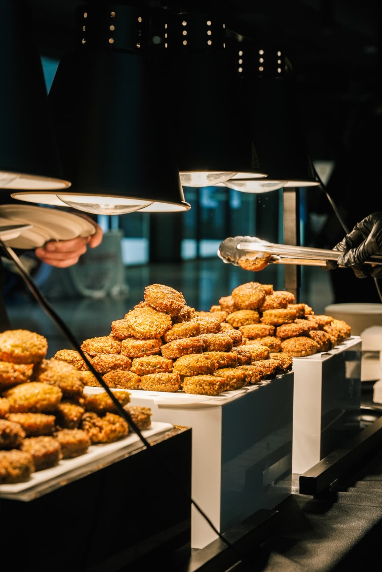 Stacks of golden fritters kept warm under heat lamps