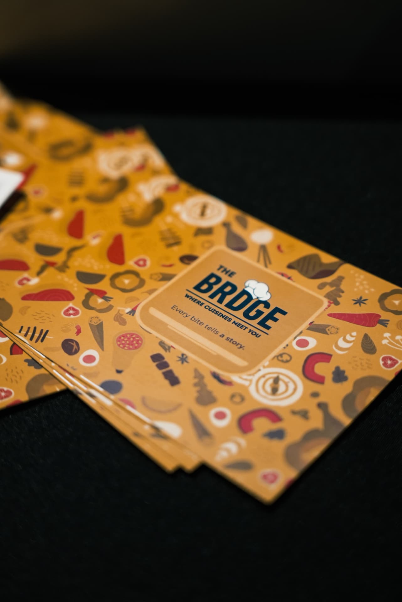 Orange BRDGE cards printed with 'Every bite tells a story'