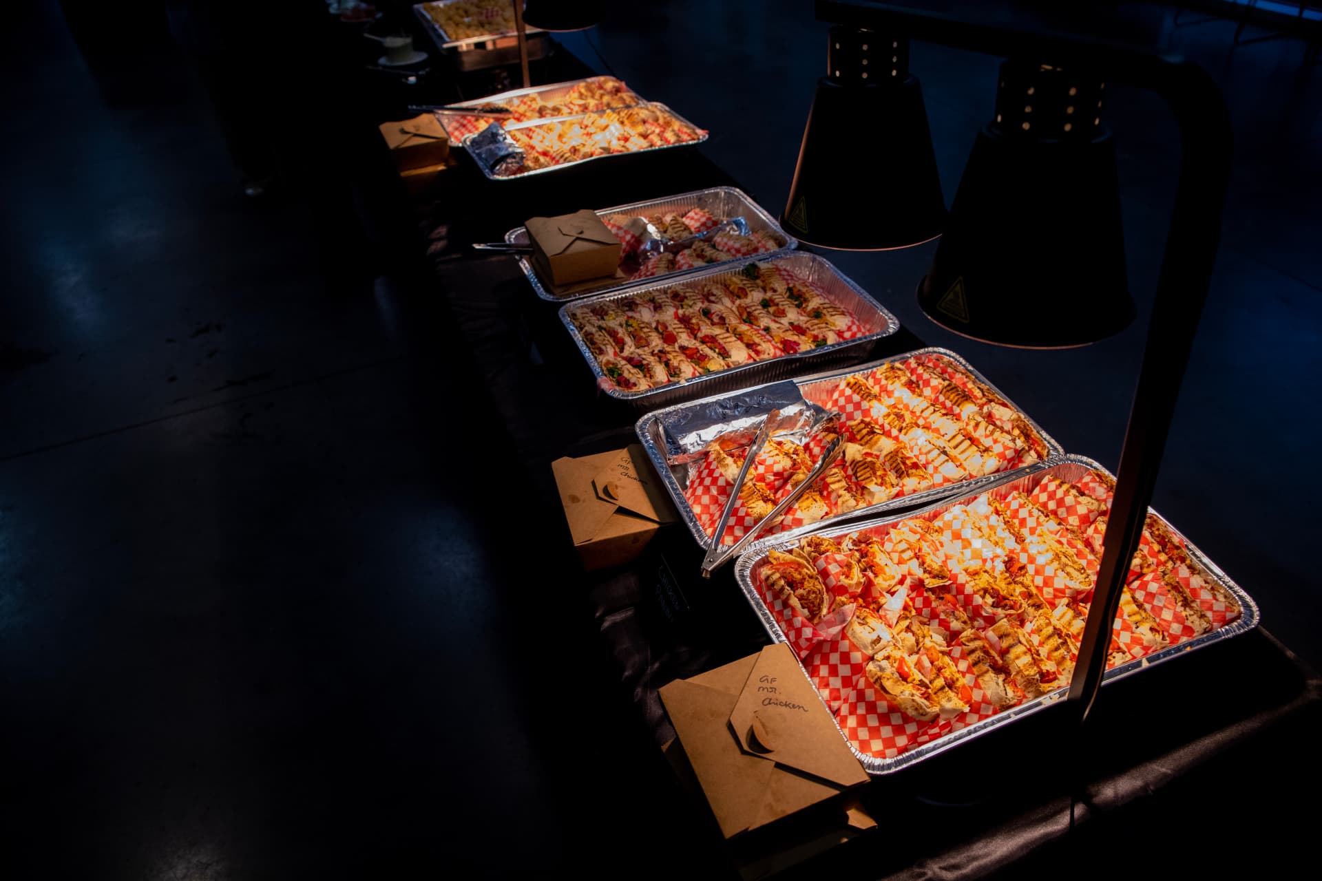 Overhead view of a buffet table with trays of wraps on red-checkered paper